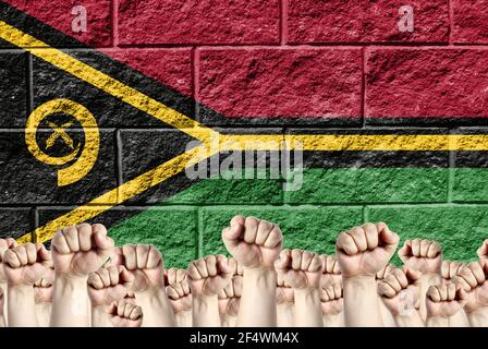 Raised fists against the background of the depicted flag of Vanuatu on a brick wall, a concept of strength and unity. Stock Photo