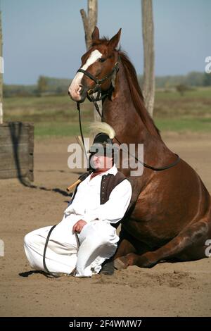 PUSZTA, HUNGARY, SEPTEMBER, 04. 2020: Hungarian herdsmen as csikos in traditional folk costume showing his trained horses in the puszta hungarian lowl Stock Photo