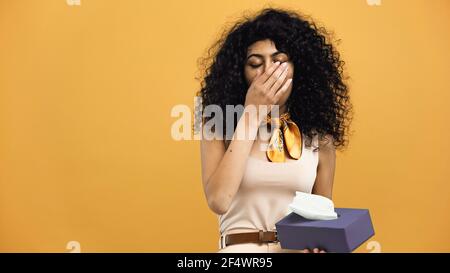 Sick hispanic woman holing napkins isolated on yellow Stock Photo