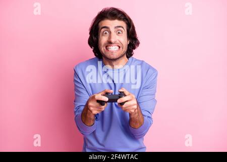 Photo of interested curly hairdo guy hold having fun playstation wear purple sweater isolated on pastel pink color background Stock Photo