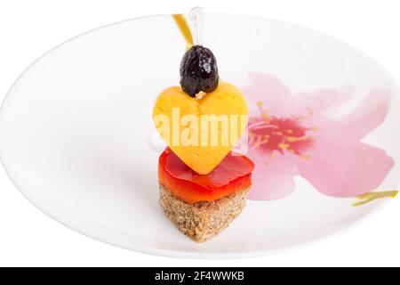 Deliicous sandwich in form of heart with cheese and olive on the plate with floral pattern. Macro. Isolated on a white background. Stock Photo