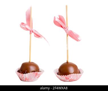 Two delicious chocolate glazed candies on stick with pink silk ribbon. Macro. Isolated on a white background. Stock Photo