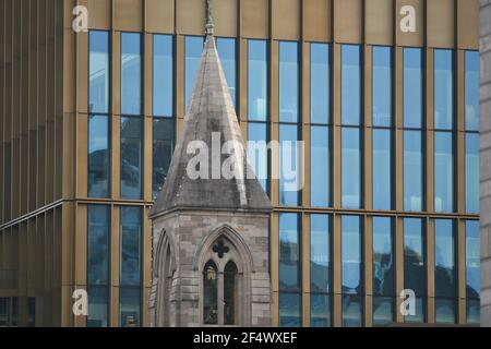 Old stone bell tower top with a modern glass building facade on the background in Dublin, Ireland. Stock Photo