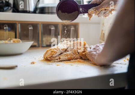 Low angle view of a woman making home made gnocchi dough dustin flour over it. Stock Photo