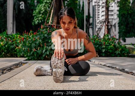 Asian sport girl doing stretching, yoga fitness and plank exercise outside. Fit young thai woman doing training workout in morning. Stock Photo