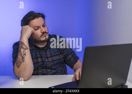 Spanish bearded man with tattoos working on a laptop Stock Photo