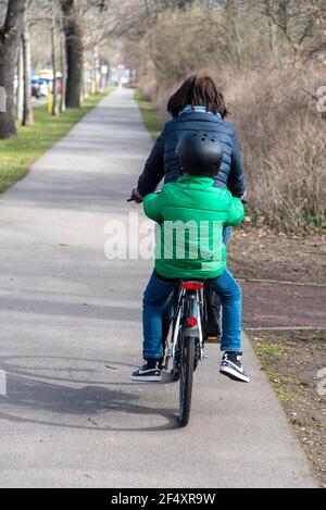 Magdeburg, Germany. 20th Mar, 2021. A woman is cycling on a path in Magdeburg, a child with a crash helmet is sitting on the carrier. Credit: Stephan Schulz/dpa-Zentralbild/ZB/dpa/Alamy Live News Stock Photo