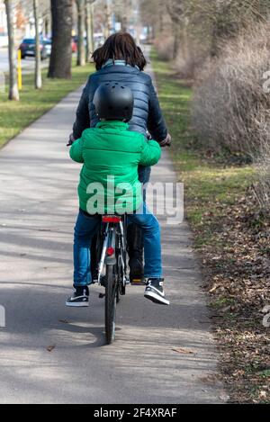 Magdeburg, Germany. 20th Mar, 2021. A woman is cycling on a path in Magdeburg, a child with a crash helmet is sitting on the carrier. Credit: Stephan Schulz/dpa-Zentralbild/ZB/dpa/Alamy Live News Stock Photo