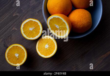 Fresh oranges in a light blue bowl on a dark wood background Stock Photo