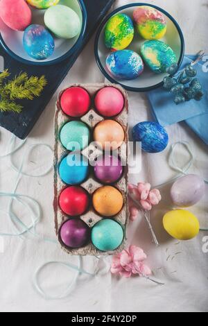 Hand-painted Easter eggs in pastel tones on a table covered with a white tablecloth. Top view. Stock Photo