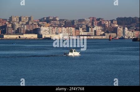 A motor yacht sailing in the bay of Santander Cantabria Spain with the city and ferry terminal behind on a calm sunny spring morning Stock Photo