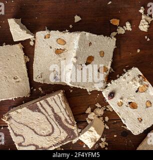Halva variety cocoa and almonds flat lay on wooden table background. Vanilla halvah or halwa pieces with nuts and chocolate. Traditional dessert confe Stock Photo