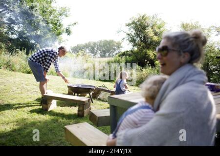 Family enjoying barbecue in sunny summer backyard Stock Photo