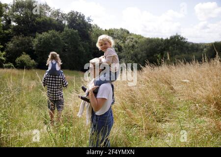 Portrait happy cute girl on shoulders of mother in sunny rural field Stock Photo