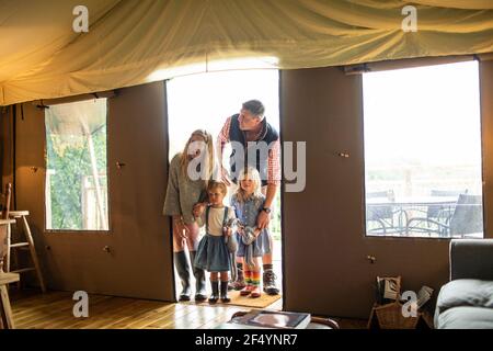 Happy family arriving in yurt cabin doorway Stock Photo