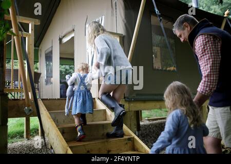 Family holding hands walking up steps to cabin Stock Photo