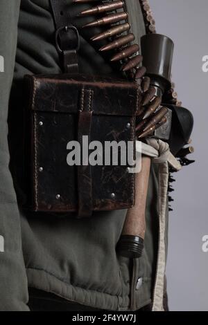 actor man in the old winter mountain uniform near the MG 42 machine gun during the World War II posing on a gray background Stock Photo