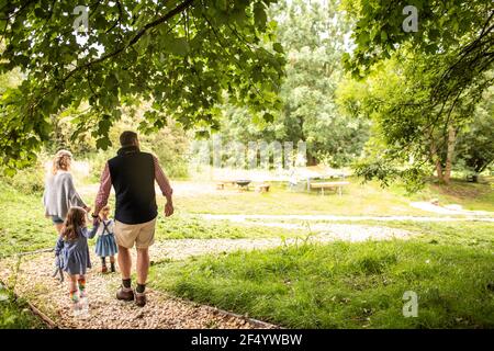 Family holding hands walking on path in idyllic park Stock Photo