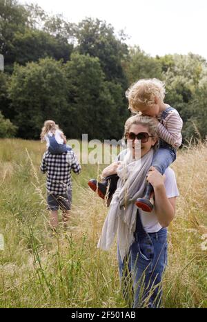 Portrait happy mother carrying daughter on shoulders in rural field Stock Photo