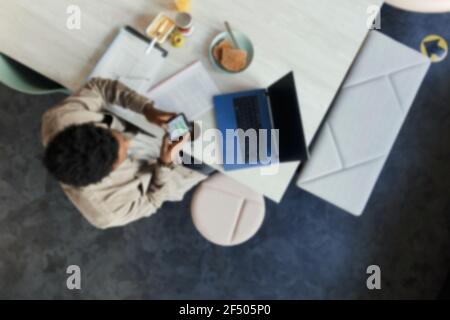 Businessman using smart phone at laptop in office Stock Photo