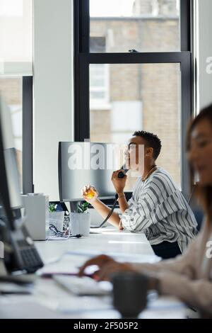 Businesswoman talking on telephone in office window Stock Photo