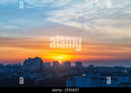Sunrise over a small town. The rising sun turned the sky golden orange. Dawn fire in the sky over a small city. Cityscape at early morning. Stock Photo