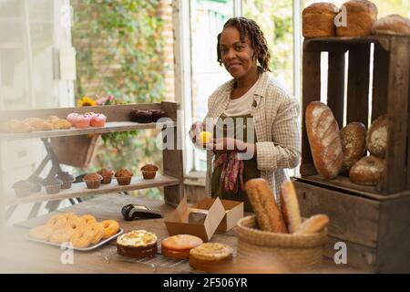 Portrait female baker arranging display in shop Stock Photo