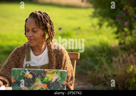 Woman working at laptop in sunny garden Stock Photo