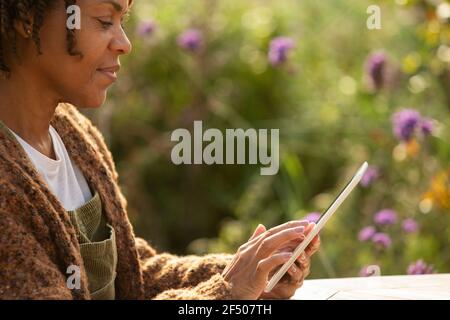 Woman using digital tablet in sunny garden Stock Photo