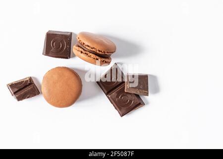 Chocolate macaroons dessert on white background top view. French meringue cookie macarons with chocolate pieces. Stock Photo