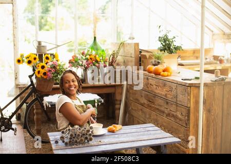 Portrait happy female florist enjoying coffee break in flower shop Stock Photo