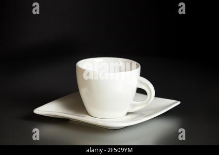 Coffee ceramic cup and saucer on a gray table against a black wall. Coffee break, rest. Close-up. Stock Photo