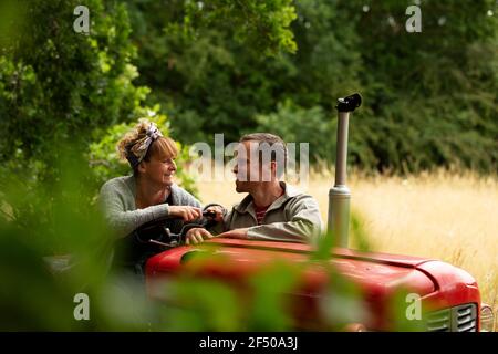Happy couple talking at tractor in orchard Stock Photo