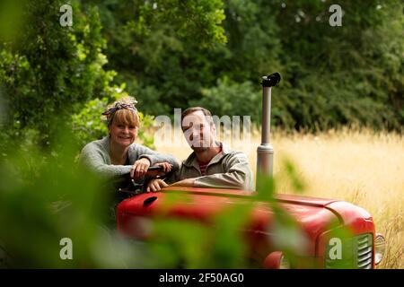 Portrait happy couple at tractor in orchard Stock Photo