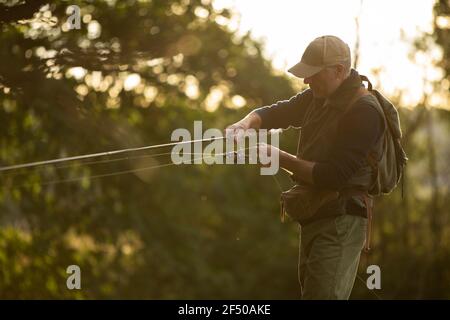 Man casting fly fishing pole at a river - Stock Image - F033/4200