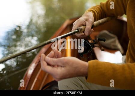 Close up man adjusting fly fishing line in boat Stock Photo
