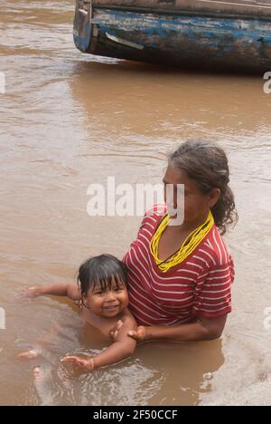 Darien Province, Panama. 07-18-2019. An indigenous grandmother is holding his grand son in the water. Stock Photo