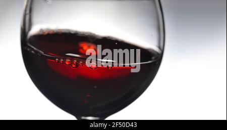 Red wine in wineglass on a grey background. Abstract splashing. Copy space for your text. Closeup. Stock Photo