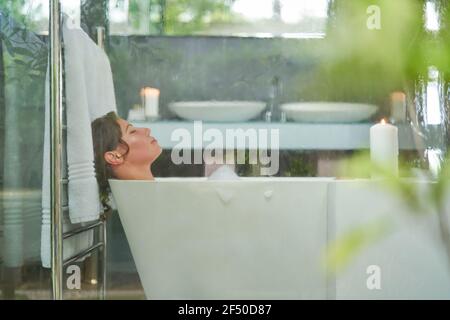 Serene woman enjoying bubble bath in modern luxury bathroom