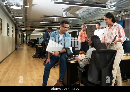 Business people meeting at laptop on desk in open plan office Stock Photo