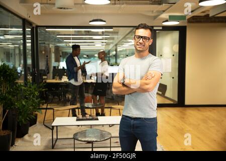 Portrait happy businessman with arms crossed in office Stock Photo