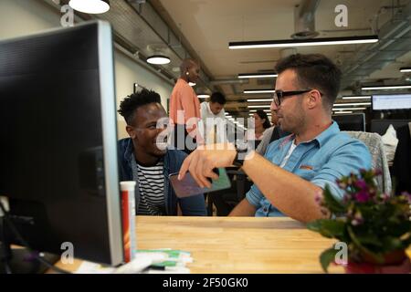 Businessmen talking at computer in office Stock Photo