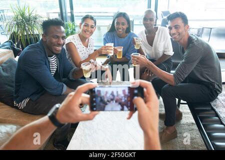 POV man with smart phone photographing friends drinking beers Stock Photo