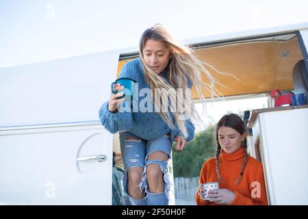 Young women friends drinking coffee in camper van Stock Photo