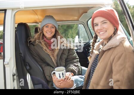 Portrait happy young women friends drinking coffee in van doorway Stock Photo
