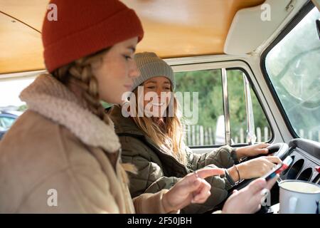 Young women friends using smart phone in van Stock Photo