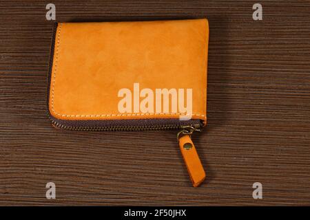 Brown leather wallet closed with zipper on wooden table Stock Photo