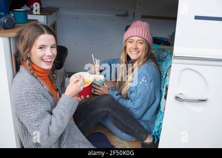 Portrait happy young women friends waiting instant noodles in van Stock Photo