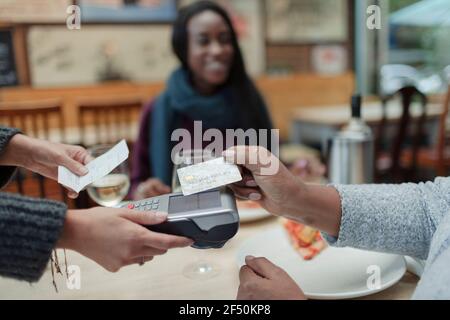 Close up woman paying waitress with smart card Stock Photo