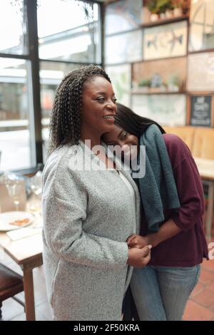 Affectionate mother and daughter hugging in cafe Stock Photo